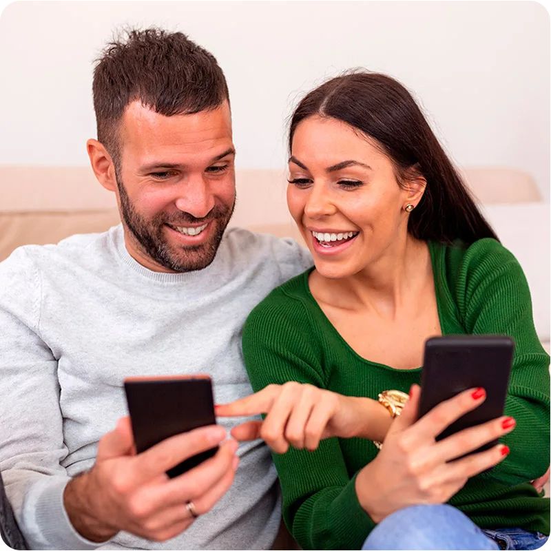 Hombre y mujer sonriendo, cada uno sosteniendo un celular 