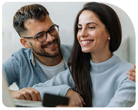 Pareja sonriendo frente a un computador inviertiendo en Fondos Mutuos