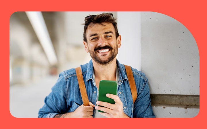 Hombre sonriendo sosteniendo su móvil