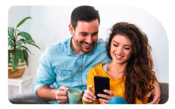 Pareja sonriendo mirando pantalla de celular