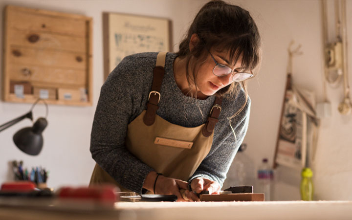 Mujer trabajando en madera sobre una mesa Mujer trabajando en madera sobre una mesa