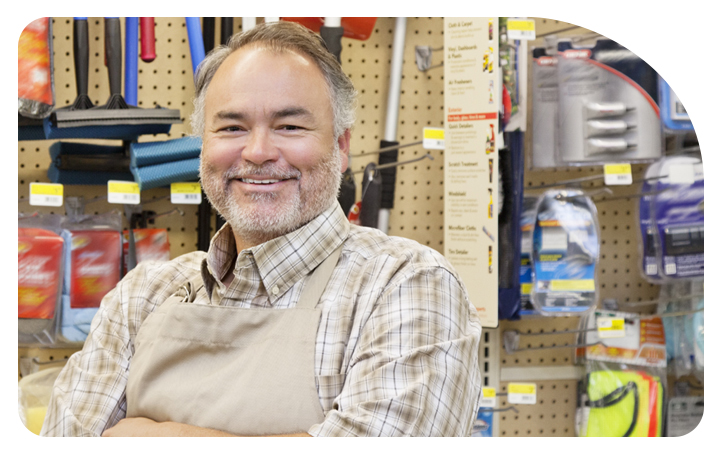 Hombre sonriendo frente al mostrador de su local comercial Hombre sonriendo frente al mostrador de su local comercial