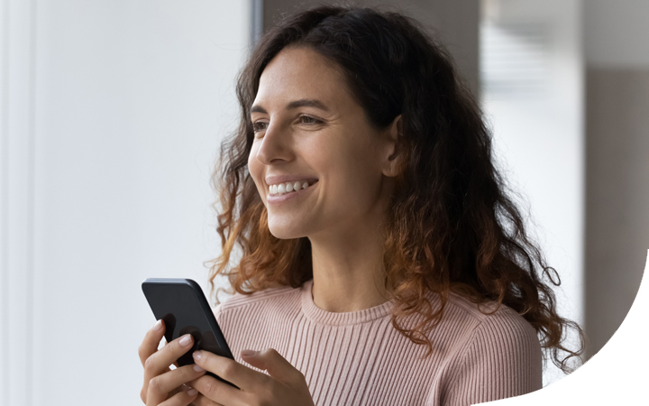 Mujer sonriendo sosteniendo celular con las manos