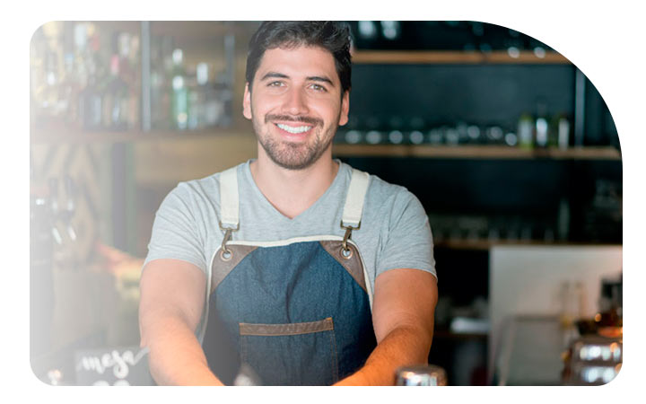 Hombre sonriendo frente al mostrador de su local comercial