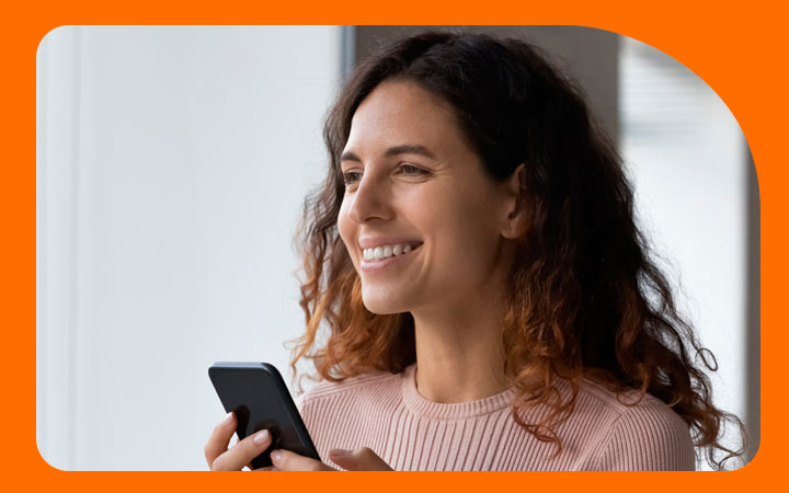 Mujer sonriendo sosteniendo celular con las manos