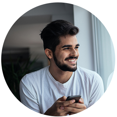 Hombre soniendo y mirando hacia su derecha con un celular en su mano