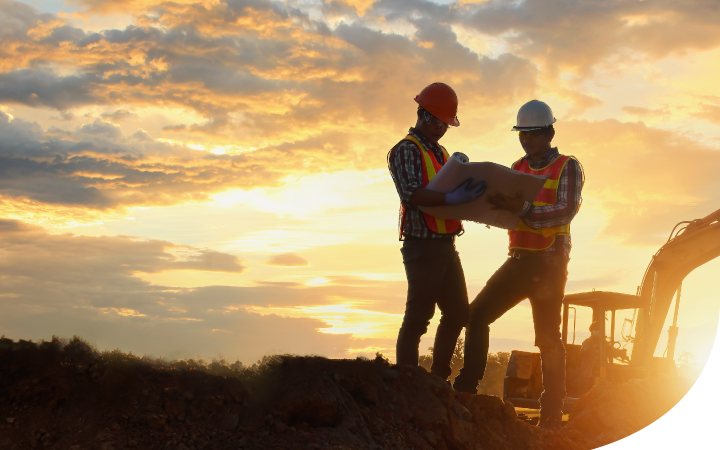 Dos Hombres trabajadores parados en medio de una obra al atardecer
