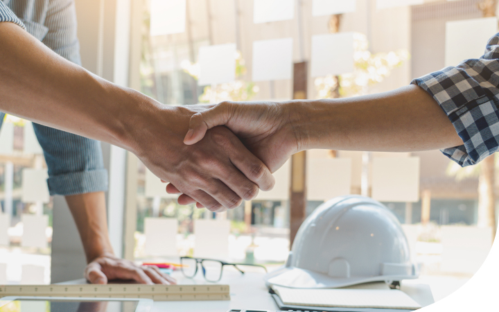 Dos manos de trabajadores estrechándose sobre una mesa