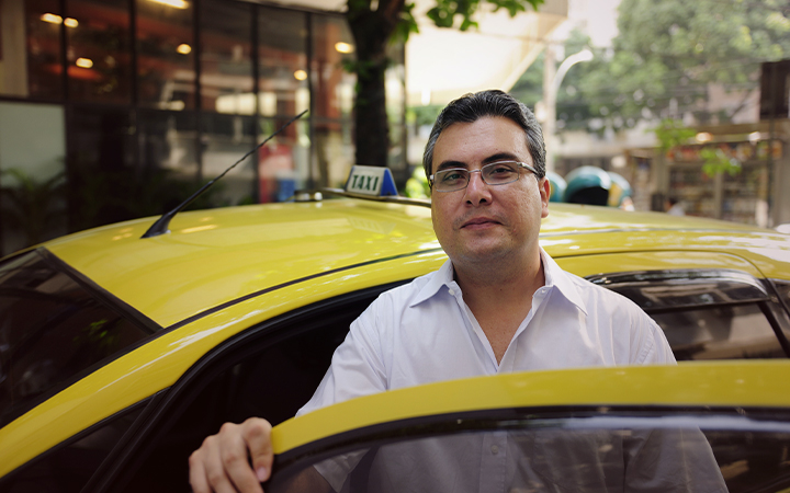 Taxista posando al lado de la puerta de su taxi