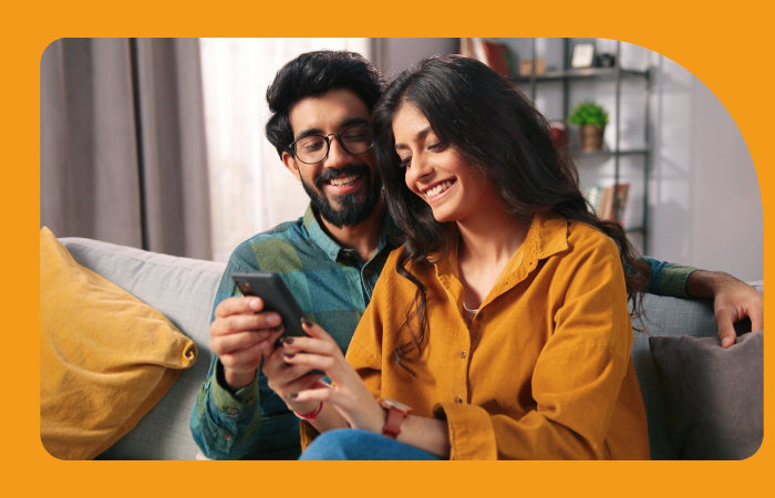 Pareja de jóvenes relajados en un sillón mirando un celular