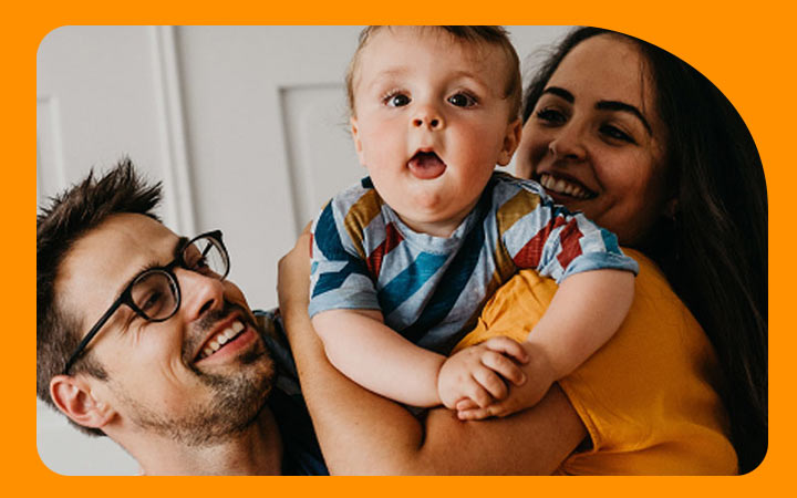 Padres sonriendo sosteniendo a su bebé