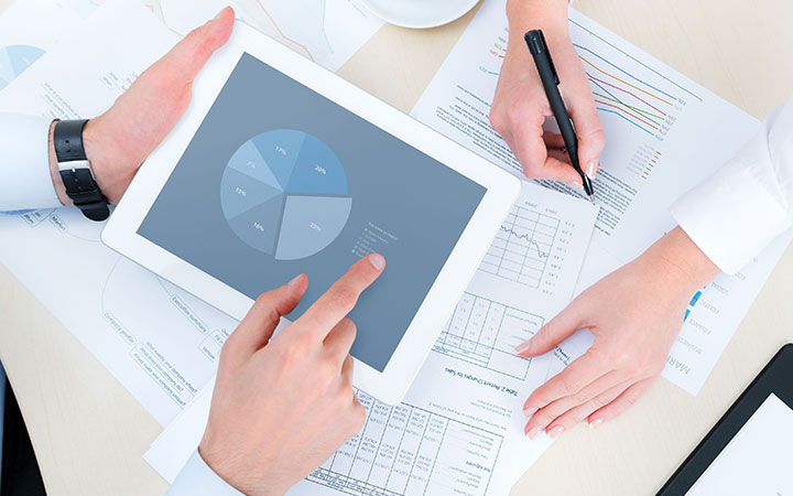 Manos revisando informes y gráfico en tablet