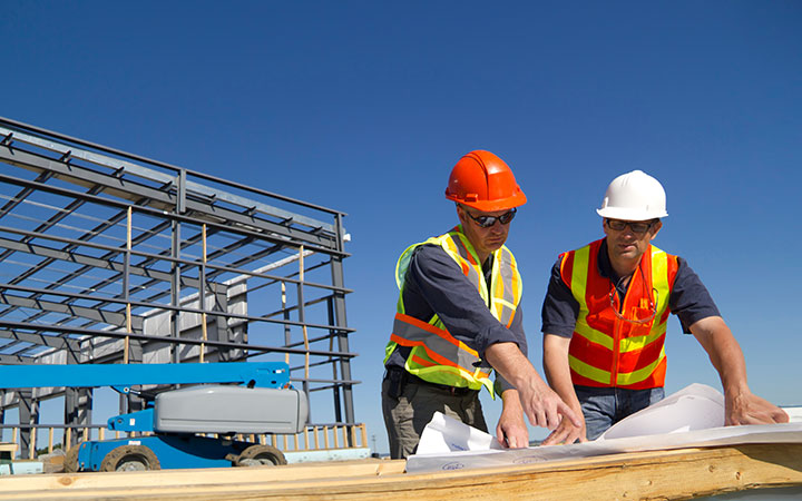 Directores de obra revisando planos en una construcción