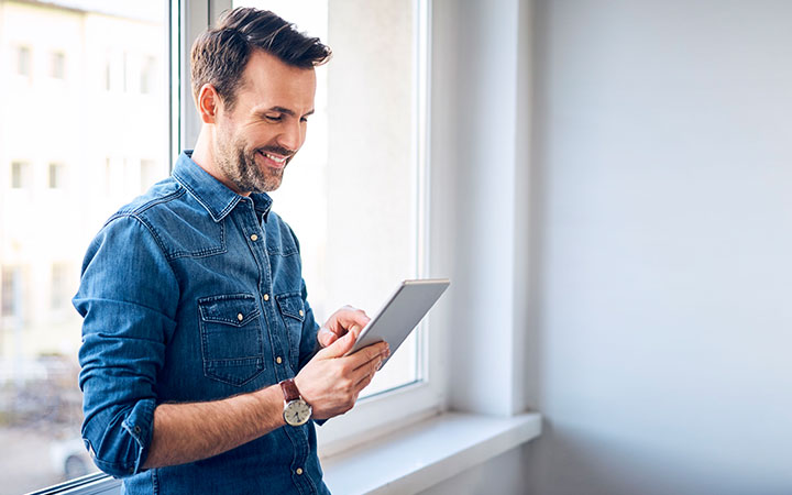 Hombre sonriendo mirando tablet