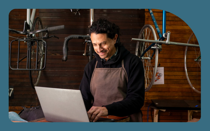 Emprendedor en su tienda de bicicletas trabajando en computador