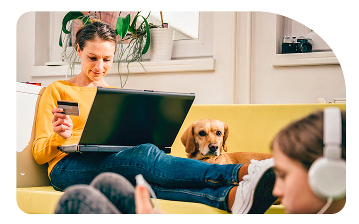 Mujer en un sillón mirando un computador sosteniendo Tarjeta BancoEstado en mano Mujer en un sillón mirando un computador sosteniendo Tarjeta BancoEstado en mano