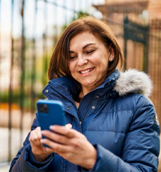 Persona con chaqueta de invierno usando un smartphone en exterior urbano